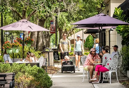 people walking down shopping street and sitting at a cafe